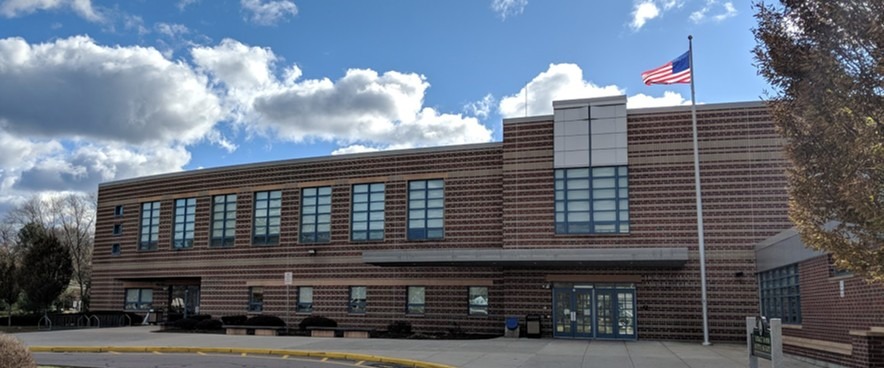 U.S. public high school facade with flag